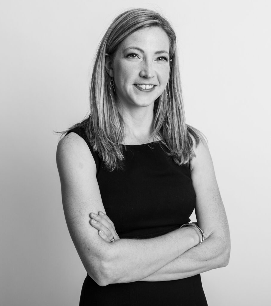 Black and white photo of Noella Sudbury, a white woman with blonde hair wearing a black sheath dress